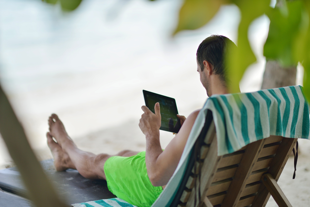 business man relaxing and use tablet computer at beautiful tropical beach